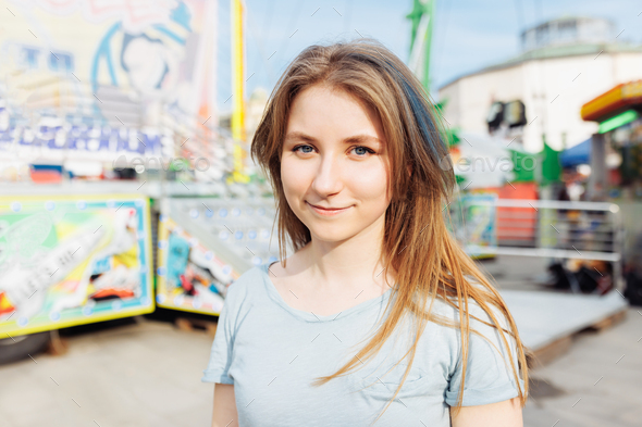 Happy young Gen Z woman with trendy blue hair in an amusement park